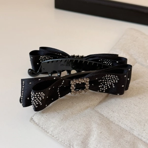 Close-up of elegant black satin ribbon bow clip with sparkling silver rhinestone trim