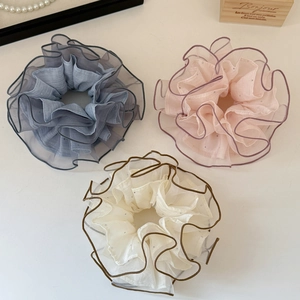 Detail of organza scrunchies in blue, pink, and beige with wavy edges and layered mesh