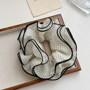 Detailaufnahme des Vintage-Haargummis mit Polka Dots und Rüschenrand auf einem Tablett