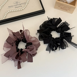 Detailed close-up of mesh bow scrunchies in black and purple with crystal pendants