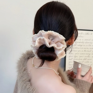 Detail view of apricot pleated scrunchie with lace edge in an elegant low bun hairstyle
