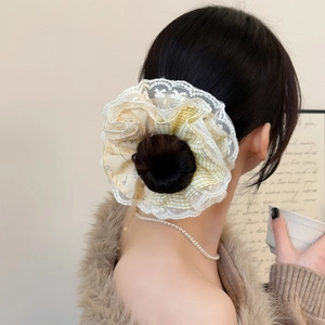 Close-up of a large yellow and blue plaid scrunchie with lace trim on a bun hairstyle