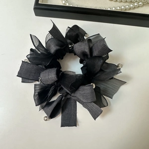 Detail of a black layered organza bow scrunchie with faceted bead charm and satin ribbon