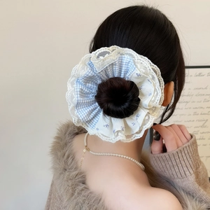 Detail of blue plaid hair scrunchie with white lace trim worn on a high bun hairstyle