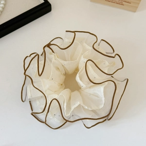 Detailed macro view of cream organza scrunchie with brown edging and tiny rhinestones