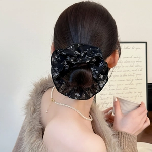Chouchou fleuri noir en tissu translucide porté sur un chignon pour un look chic