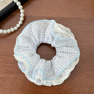 Detail of blue and white checkered scrunchie with lace edges on dark wood background