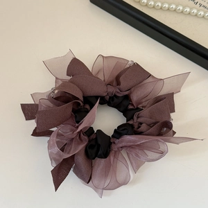 Detail of elegant dual-tone ribbon scrunchie with layered chiffon bow design in purple and black