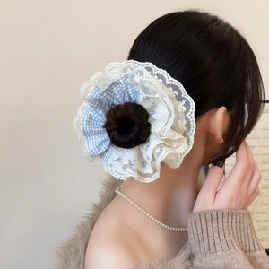 Detailed view of large layered lace scrunchie with blue plaid on a messy bun hairstyle