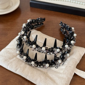 Detailed macro view of black tweed headband with white pearls and spikes embellishment