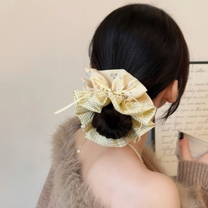Detail of yellow floral and green checkered scrunchie with a bow and pearl on hair