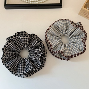Detailed view of plaid scrunchies with wavy edges in black-white and blue-white check
