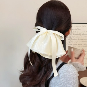Detail of cream white bow hair clip with flowing ribbons and delicate pearl edges
