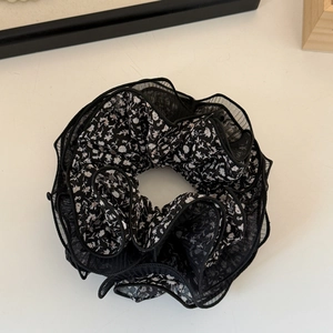 Detailed macro view of black mesh floral scrunchie with intricate ruffled fabric layers