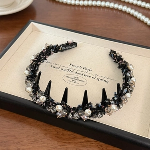 Detailed view of handmade pearl and crystal headband with chic black spikes decor