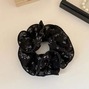 Vue détaillée d'un chouchou noir en mousseline avec d'élégants motifs floraux blancs