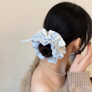 Detail of blue plaid scrunchie with floral fabric, lace, and a bow worn on hair bun