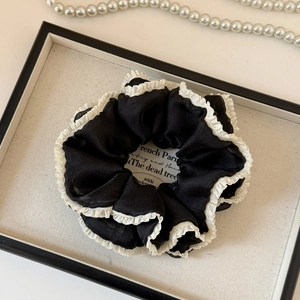 Detailed close-up of French style black scrunchie with elegant white pleated mesh edges
