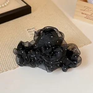 Pince à cheveux rose en tulle noir plissé avec strass argentés sur fond chaleureux