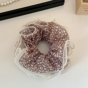 Detailed view of brown floral mesh hair scrunchie with white ruffled tulle edges