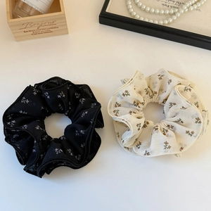 Lot de chouchous en tulle à fleurs noir et beige présentés sur une boîte vintage