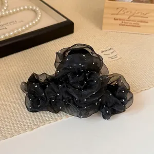 Détail de la pince à cheveux en tulle noir avec strass brillants sur fond en bois