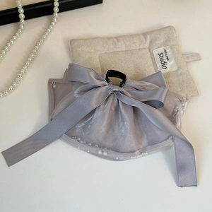 Detail of grey silk bow hair claw clip with delicate pearl trim on minimalist beige background