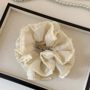 Detail of cream oversized pleated scrunchie with ruffled edges and silky organza texture