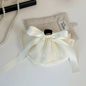 Close-up of beige ribbon hair claw with organza ruffles and delicate pearl trimming
