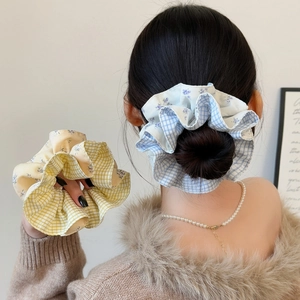 Detail of blue and yellow plaid scrunchies styled on a bun hairstyle with lace edges