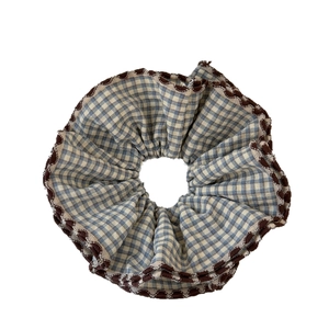 Blue and white checkered fabric scrunchie with wavy brown trim and ruffled texture
