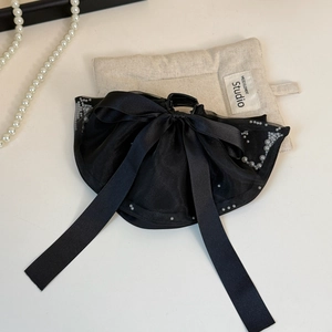 Detailed macro of a black satin bow hair claw clip with elegant pearl bead edge trim