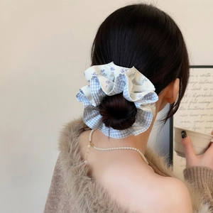 Close-up of a sweet blue plaid and floral fabric scrunchie worn on a low bun hairstyle