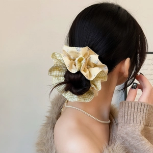 Detailed shot of yellow plaid and purple floral scrunchie on a ponytail hair tie
