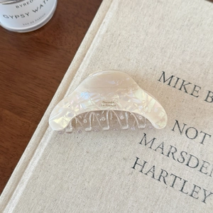 Pince à cheveux crème irisée avec texte Barrette La France sur un livre en lin