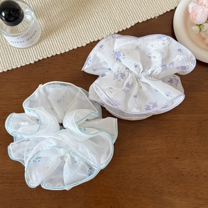 Dettaglio di elastici scrunchie in tulle a fiori blu e viola su tavolo di legno