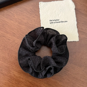 Dettaglio di un elastico per capelli nero a pois in pizzo su fondo in legno
