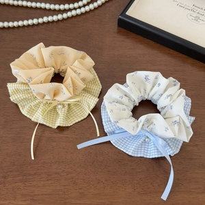 Detailed shot of yellow and blue plaid scrunchies with floral fabric and pearl bow