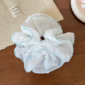 Dettaglio di un elastico in rete bianca con fiori blu su un tavolo di legno rustico