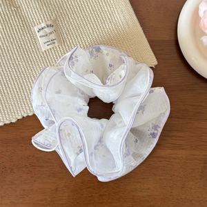 Primo piano di un elastico per capelli in mesh floreale con cuciture viola sul tavolo
