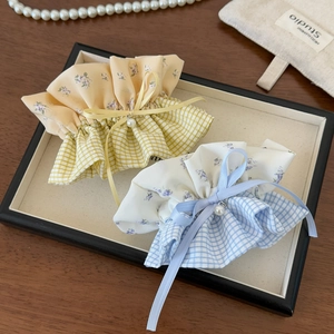 Detail of yellow and blue plaid scrunchies with delicate pearl bows on a display tray