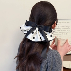 Elegant polka dot satin bow hair clip with black ribbon accent on model back view