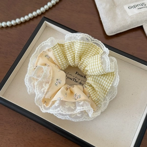 Close-up of yellow plaid and floral fabric scrunchie with layered white lace edges