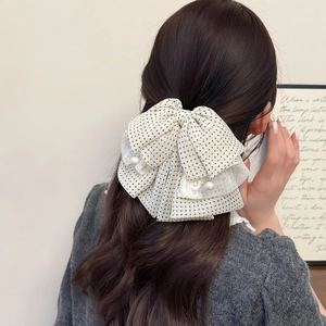 Polka dot mesh bow hair clip with white lace and pearl pendants on wavy brown hair