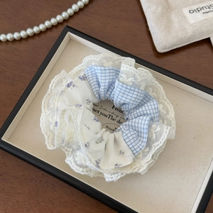 Close-up of yellow and blue plaid scrunchie with floral fabric and white lace trim