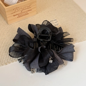 Détail de la pince à cheveux 13cm en organza noir avec gouttes de cristal sur un tapis