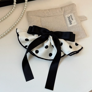 Close-up of a vintage polka dot satin bow hair clip with elegant black trim detailing