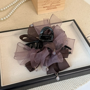 Détail de la pince à cheveux avec nœud en organza café et perles sur présentoir