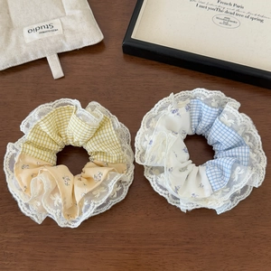 Detail of yellow and blue plaid scrunchies with white lace trim on wooden background