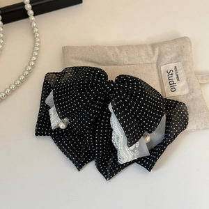 Close-up of black polka dot mesh bow hair clip with lace edges and pearl charms